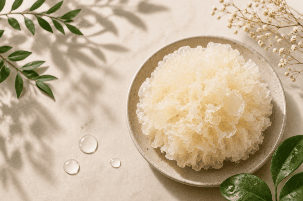 Tremella mushroom in a ceramic bowl with green leaves and water droplets, representing natural skincare and hydration.