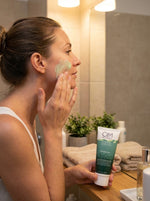Woman applying facial cream to her face in a bathroom setting
