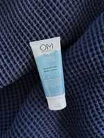 Baby Lotion - lifestyle on a soft blue blanket | OM Botanical