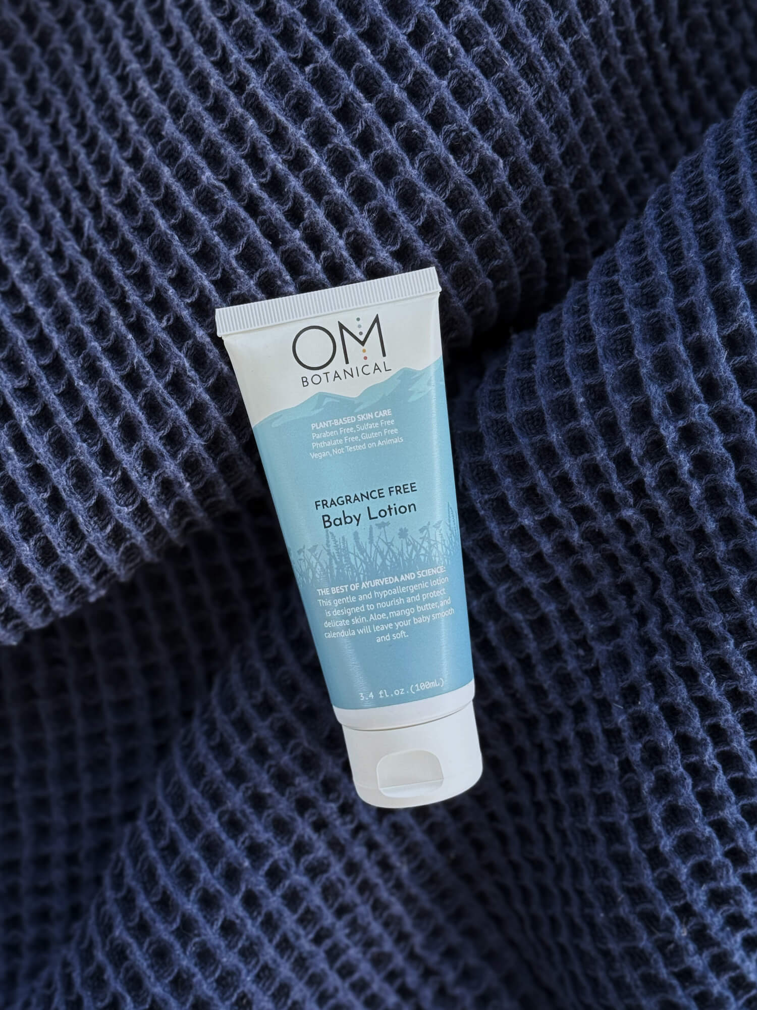 Baby Lotion - lifestyle on a soft blue blanket | OM Botanical