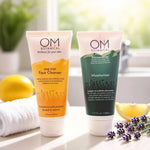 Two tubes of OM Botanical skincare products on a surface with lemons and lavender.