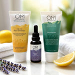 OM Botanical skincare products including a face cleanser, vitamin C serum, and moisturizer on a white surface with lemon slices and lavender.