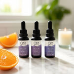 ABC Super Serums Trio featuring Bakuchiol, Vitamin B3, and Vitamin C serums in dropper bottles on a marble counter with orange slices and candle.